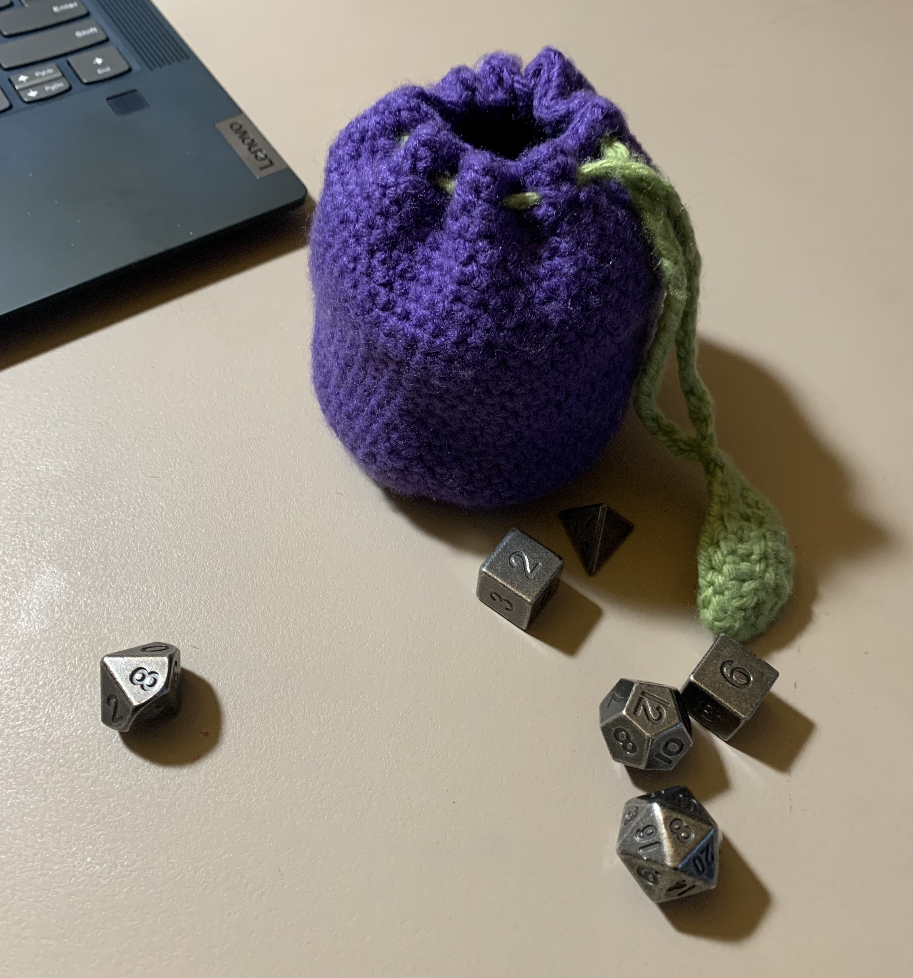 A purple dice bag with a leaf-shaped drawstring