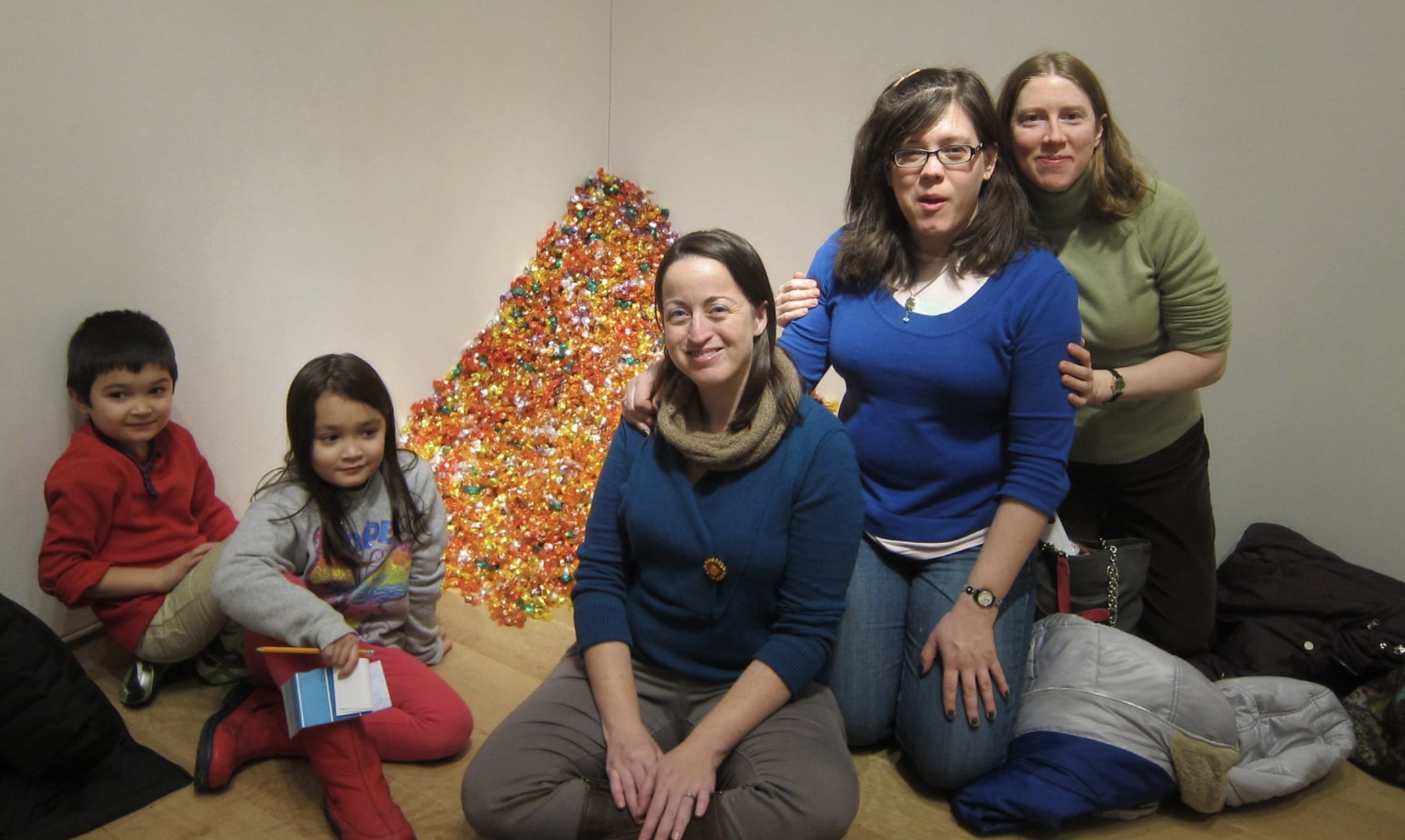 A picture of a group of people posing next to a large pile of candy in a museum.